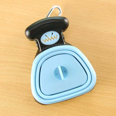 Blue foldable dog pooper scooper with black handle and carabiner clip on a wooden surface