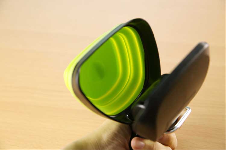Green collapsible scoop bowl of the foldable pooper scooper folding flat in one hand