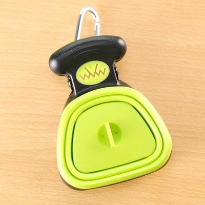 Green foldable dog pooper scooper hanging by its carabiner clip