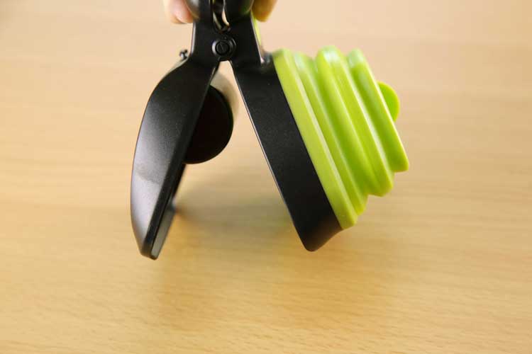 Hand holding the green foldable dog pooper scooper folded flat for storage