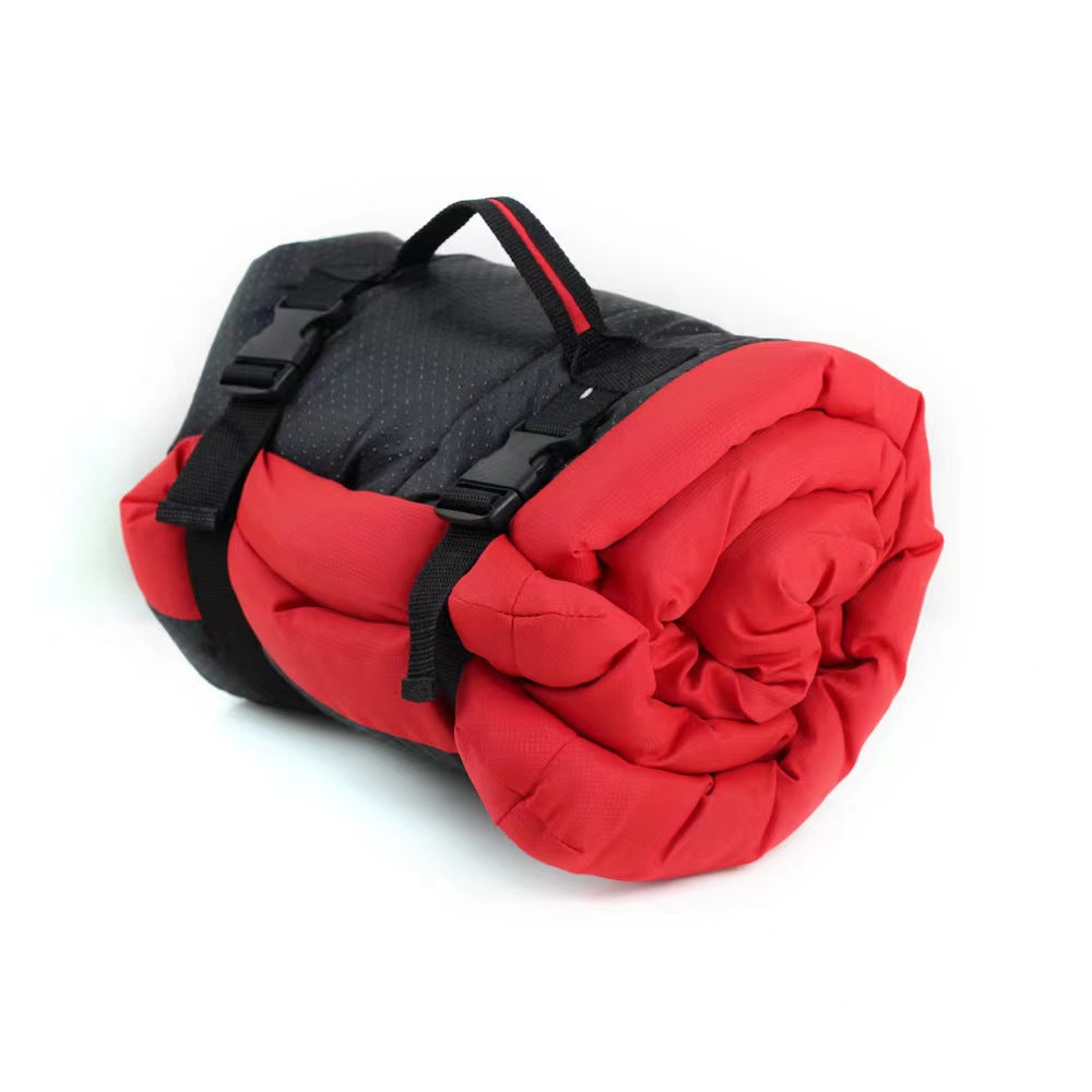 Red roll-up dog bed rolled and secured with black straps and a carry handle on a white background.