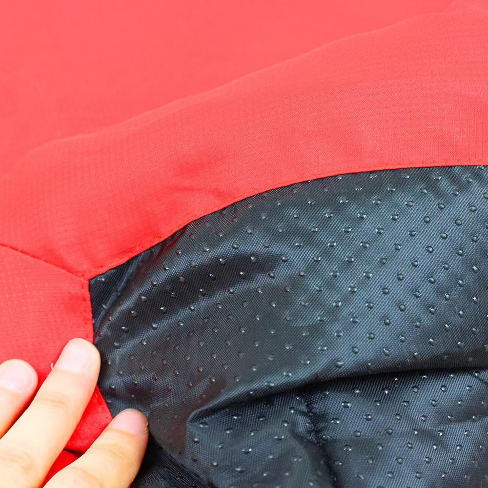 Hand folding back the corner of the red dog bed to show the black, water-resistant textured fabric underneath.