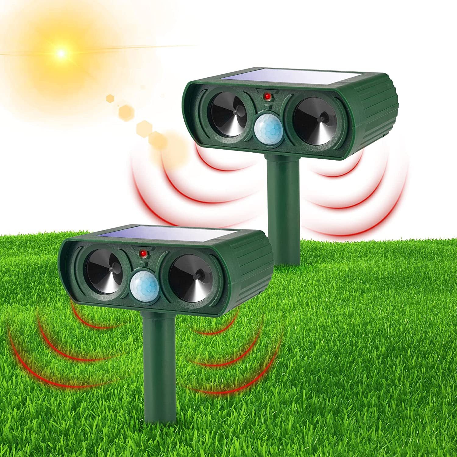 Two green solar repellents staked in thick green grass with their red motion sensors lit, sending out red ultrasonic waves as the sun shines overhead.