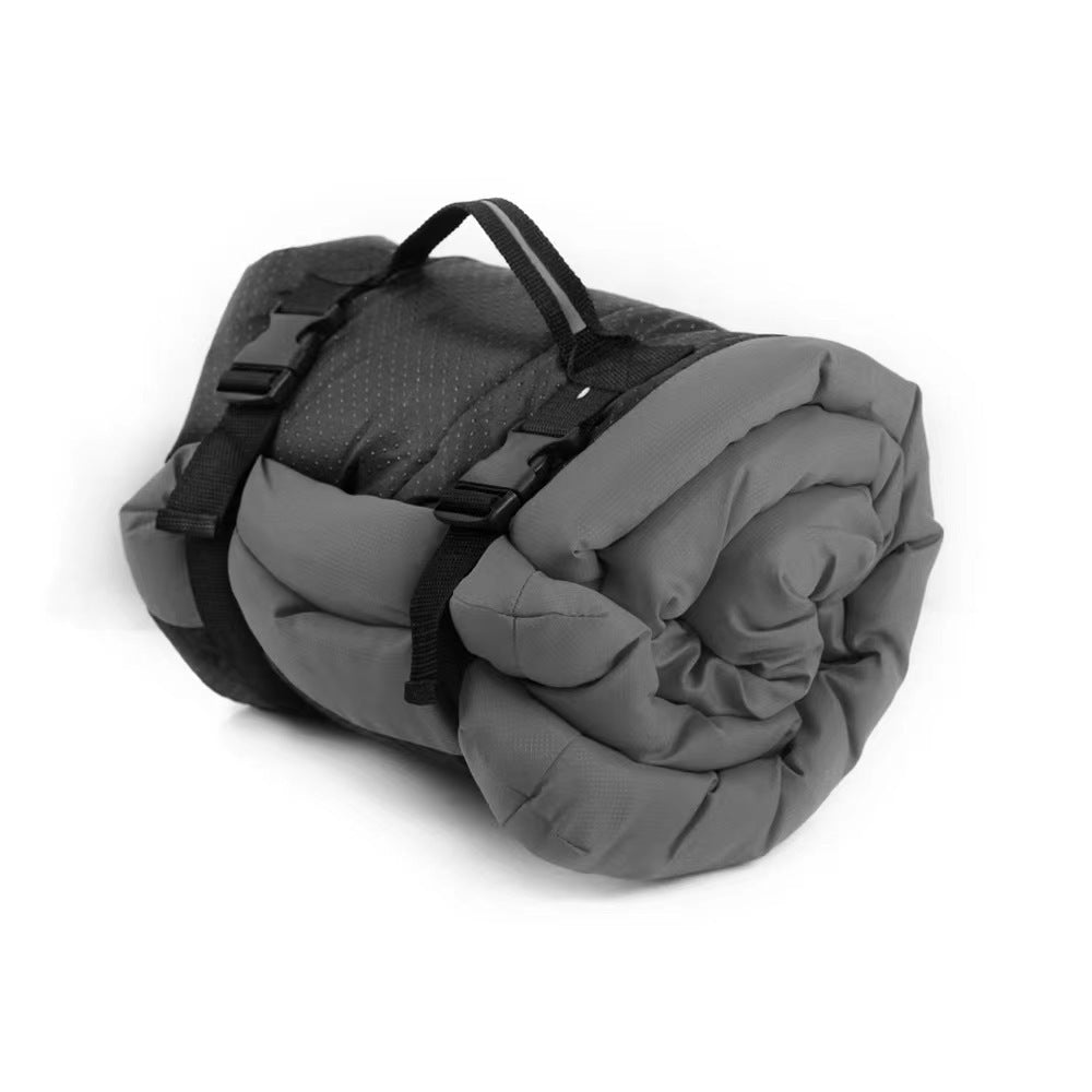 Gray roll-up dog bed rolled and secured with black straps and a carry handle on a white background.