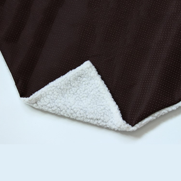 Corner of the dog kennel mat folded back to show the soft white sherpa fleece underside beneath the dark brown top