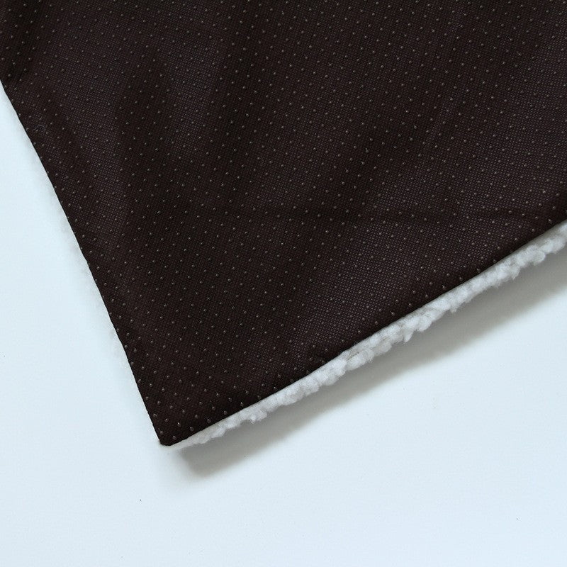 Dog kennel mat laid flat showing the brown dotted top fabric with the white sherpa lining peeking out along the edge